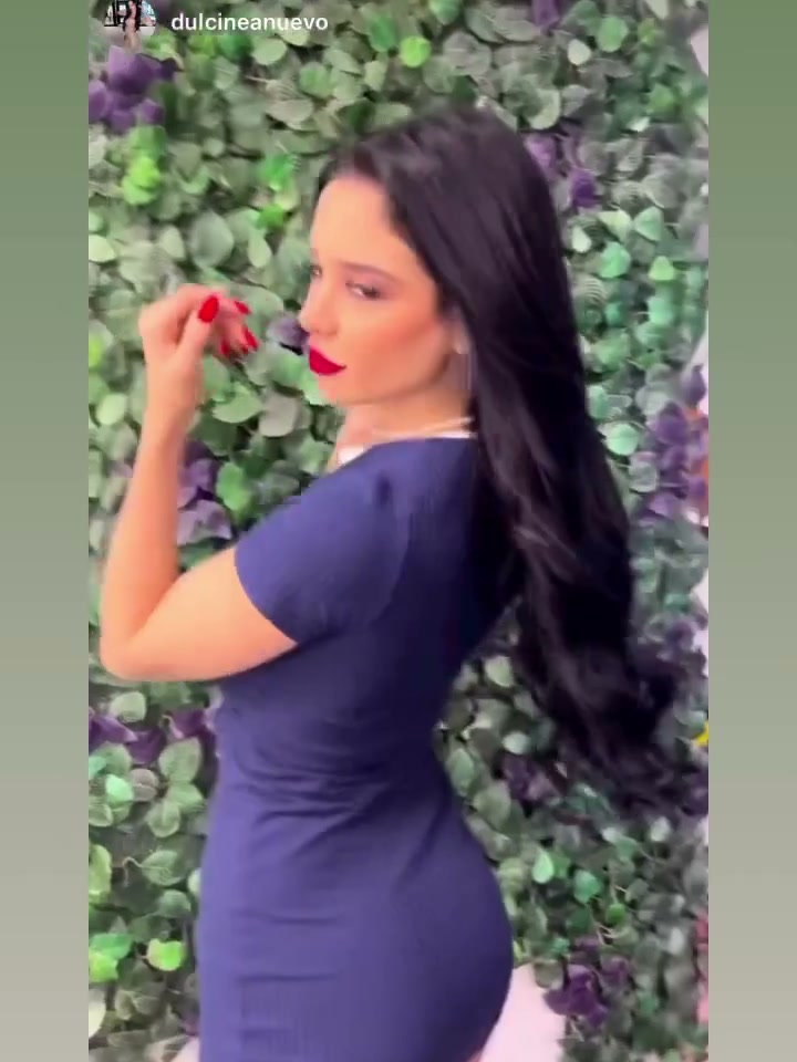 Long, glossy dark hair with extensions against the salon's leaf wall