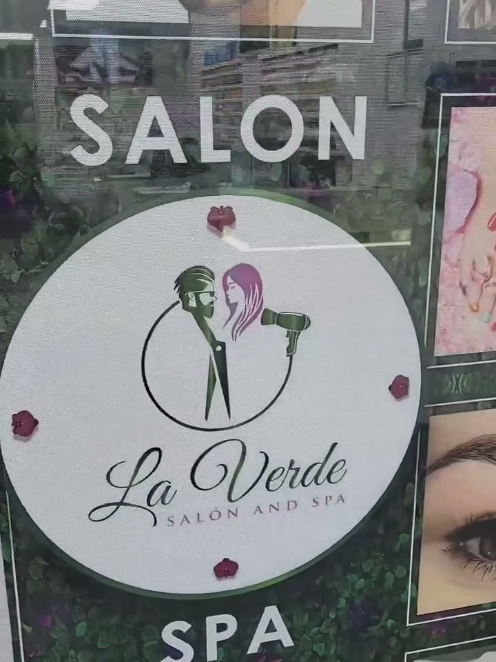 The salon's front window with the La Verde logo and lash and nail posters